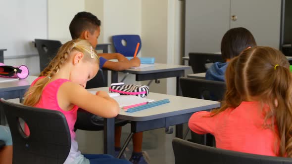 Multi-ethnic schoolkids studying at desk in a classroom at school 4k alt