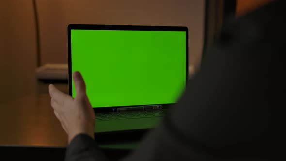 Unrecognizable Man Making Online Call Via Laptop Webcam with Chromakeyed Display alt