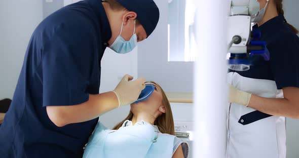 A Male Dentist Performs a Procedure for Removing a Cofferdam to Patient alt