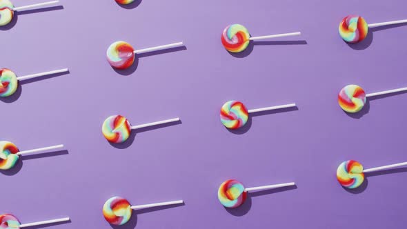 Video of rows multicoloured lollipops on blue background alt