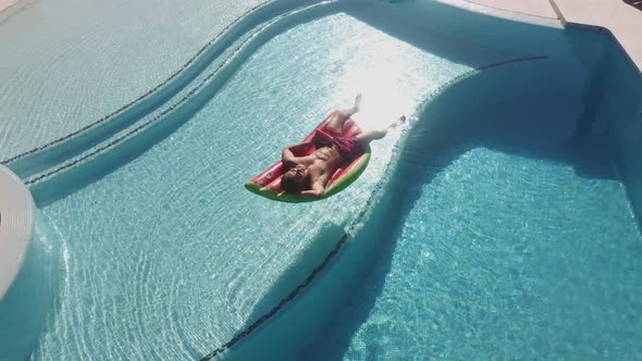 Drone Over Man Relaxing On Lilo In Pool alt