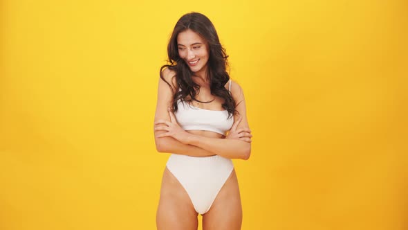A smiling brunette woman wearing swimsuit laughing to the camera alt