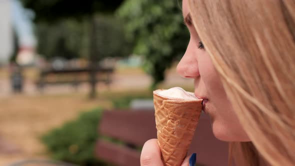 The Girl Eats an Ice Cream Cone on the Street of the City alt