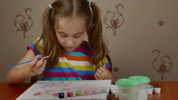 A Cute Little Girl is Happy to Paint While Sitting at the Table