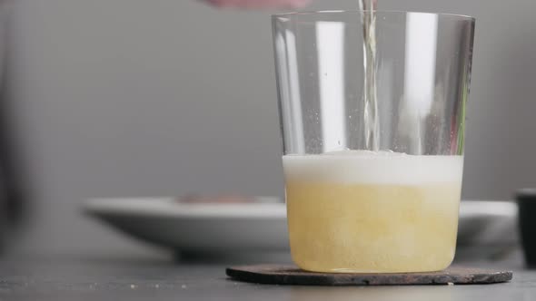 Pour Apple Cider in a Tumbler Glass on Concrete Countertop with Window on Background alt