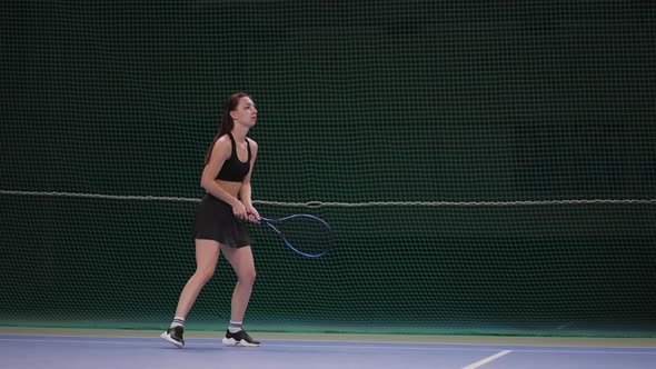 Young Pretty Brunette Woman is Learning to Play Tennis on Indoor Court Hitting Ball By Racquet Slow alt