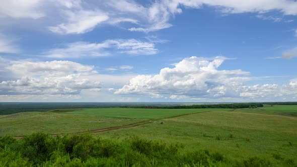 Timelapse of beautiful white clouds floating across the blue sky over green hills alt