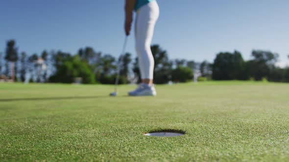 Caucasian female golf player taking shot from bunker standing on golf field alt