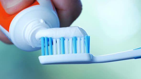 Dental Health - Squeezing White Toothpaste From a Tube Onto a Toothbrush.