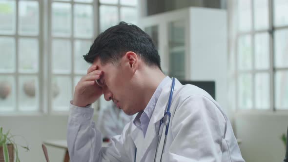 Asian Man Doctor Is Using Desktop Computer And Headache In Workplace. Medical Concept alt