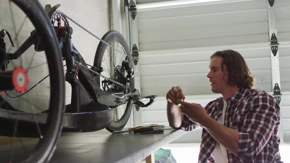 Focused caucasian man repairing bike using tools in garage alt
