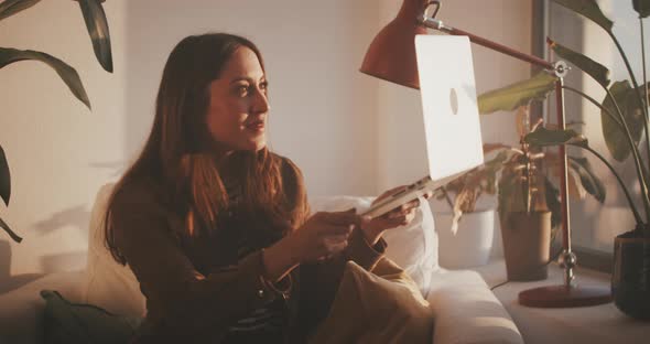 Woman lifts laptop to show viewer her apartment alt