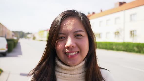 Closeup outdoor portrait of a happy Asian woman with long straight hair and smile face alt