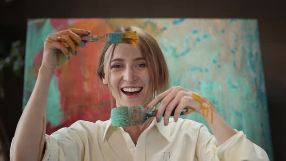 Young Artist In Art Studio With Brushes In Her Hands. alt