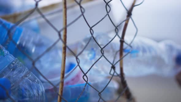 Female Hand Putting Empty Plastic Water Bottle in Special Collector on Sea Beach alt
