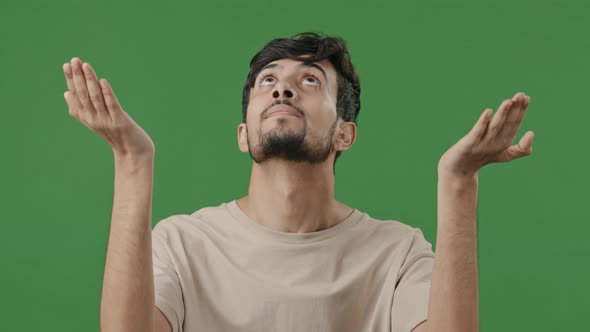 Portrait of Hopeful Arabic Hispanic Brunet Adult Man Want Blessing Standing on Green Background alt