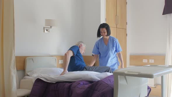 Slow Motion of Asian Female Doctor Helping Elderly Man Getting Up From Bed in the Hospital alt