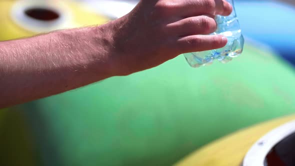 Man throwing away empty,  plastic bottle into recycling bin alt