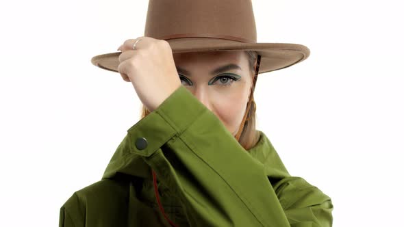 Woman in a Autumn Look in Studio in Green Parka and Hat Turns and Poses To the Camera alt
