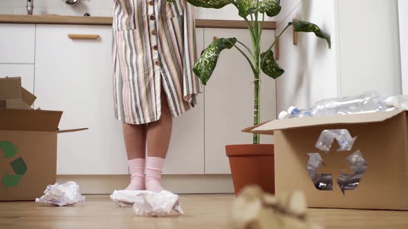 A Girl Sorts Garbage Into Boxes For Recycling Reuse, A Young Girl Stands At The Forge Throws Paper alt