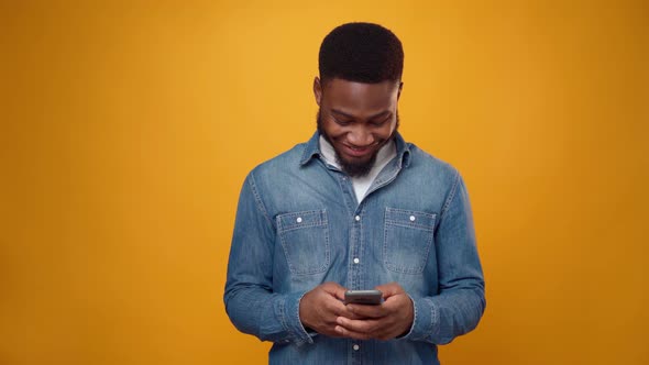Young African American Man Holding Smartphone Celebrating Victory alt
