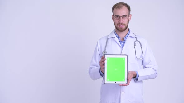 Happy Bearded Man Doctor Presenting While Showing Digital Tablet