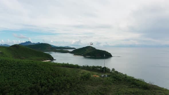 Helicopter hovers at telecom tower delivering fuel for generator on island, Fiji alt