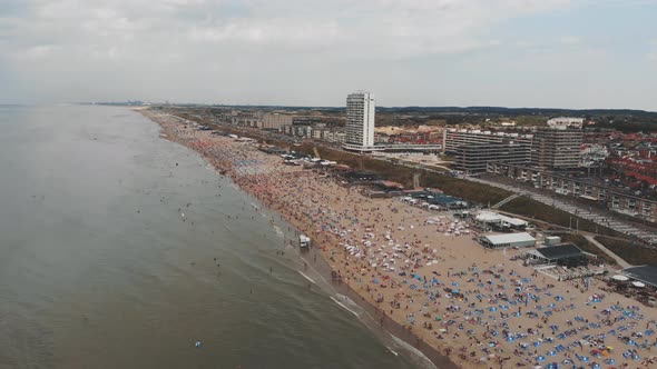 Aerial footage of a crowded beach along near Zandoort, Netherlands of the North Sea. alt
