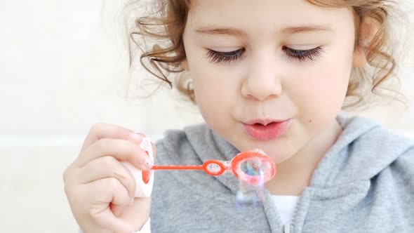 Small Caucasian Girl Blowing Soap Bubbles Close Up
