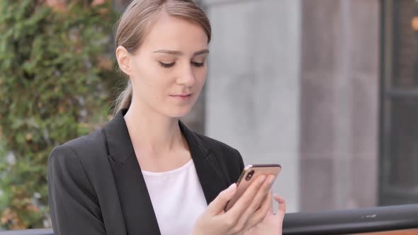 Young Businesswoman Using Smartphone Sitting Outdoor alt
