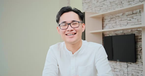 Excited guy in glasses shakes hand at online meeting alt