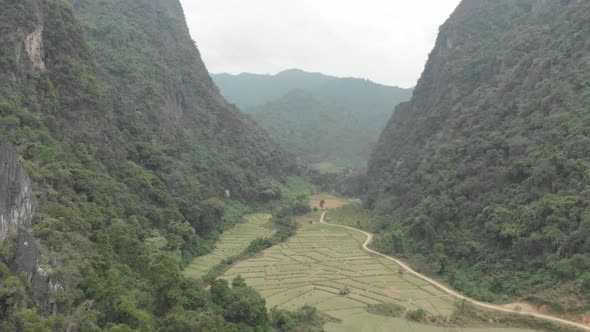 Aerial: flying over scenic cliffs rock pinnacles tropical jungle rice paddies alt