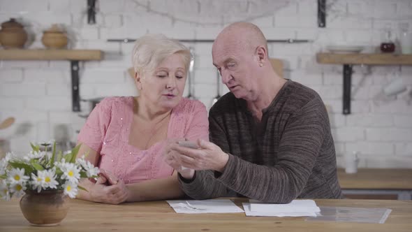 Mature Caucasian Baldheaded Man Blaming His Wife Because of Overspending. Senior Couple Dealing alt