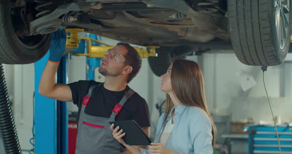 Manager Checks Data on a Tablet Computer and Explains the Breakdown To a Mechanic. Car Service alt