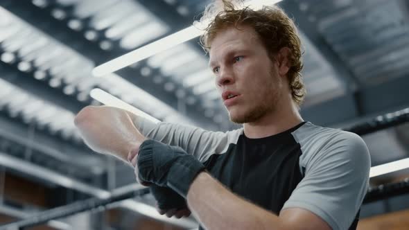 Strict Fighter Dreaming About Battle in Sport Club. Kickboxer Warming Up Wrists alt