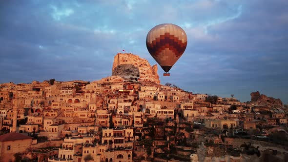One Hot Air Balloon is Flying Close to Goreme City Built on Rock Filmed By Drone alt