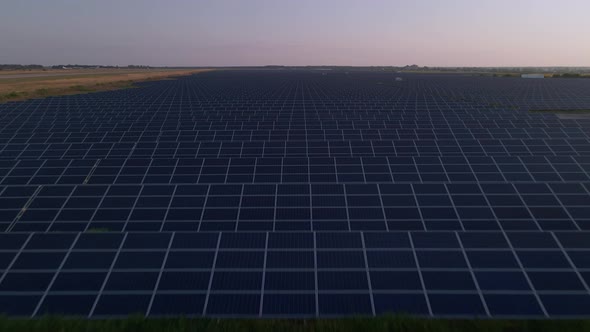 Aerial Drone View of Large Solar Panels at a Solar Farm at Bright Sunset in Early Winter alt