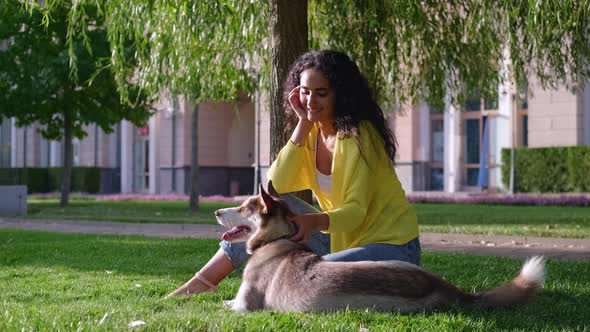 Rest in Park with Dog Young Woman and Her Pet are Sitting on Green Grass alt