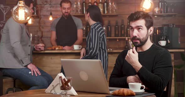 A Man Having an Online Call at His Laptop While Working in a Coffee Shop alt