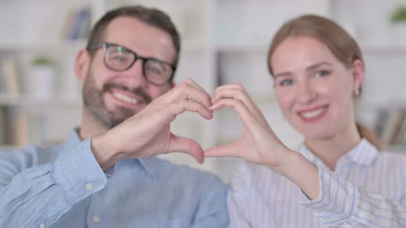 Portrait of Happy Young Couple Showing Heart Sign with Hands alt