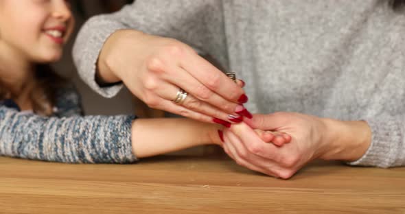 Mother helping to cut her girls daughter fingernails by clipper at home alt