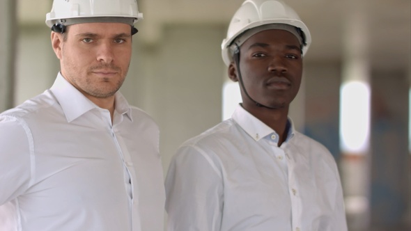 Two businessman looking at camera inside construction site