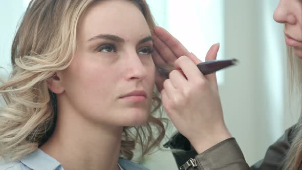 Professional Make Up Artist Applying Powder To a Young Model Face alt
