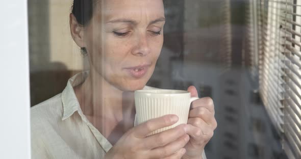 Woman with Beverage By the Window alt