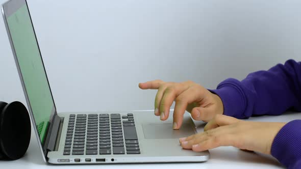 Hands of a mixed-race woman writing a text on a laptop keyboard in close-up.