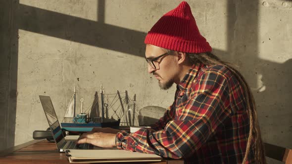 Cheerful American Hipster Working Remotely From Home on Netbook Laptop Smiling Male Freelancer alt