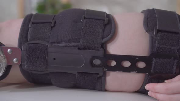 Female Leg with Orthosis Knee Brace After Injury on the Medical Couch alt