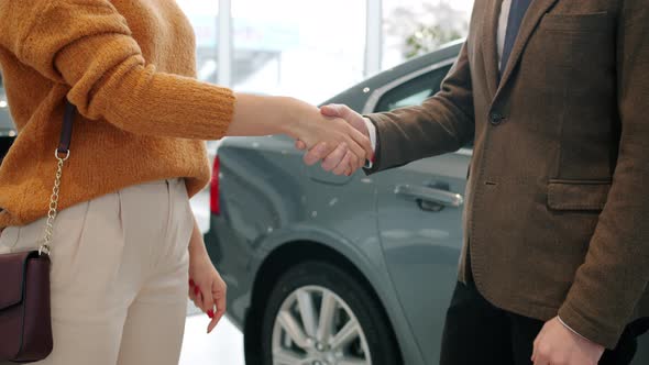 Woman Getting Car Keys From Salesman Then Shaking Hands To Celebrate Successful Deal alt