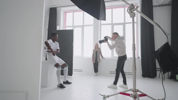 Photographer is Capturing Professional Football Player with Ball in Studio Content for Magazine alt