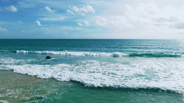 Drone shot sea waves breaking on sandy coastline foamy waves at Hawaii.